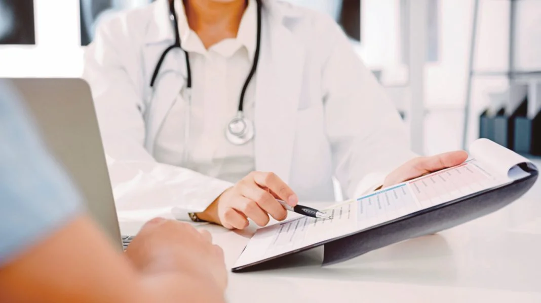 Young Asia female doctor in white medical uniform using clipboar