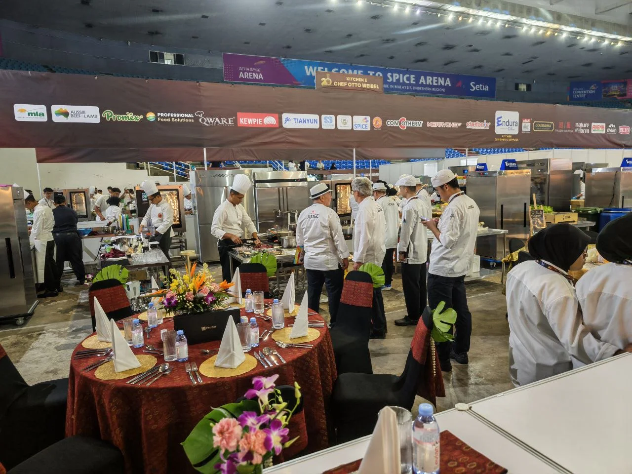 Chefs at work in the competition kitchen, with judges watching on.