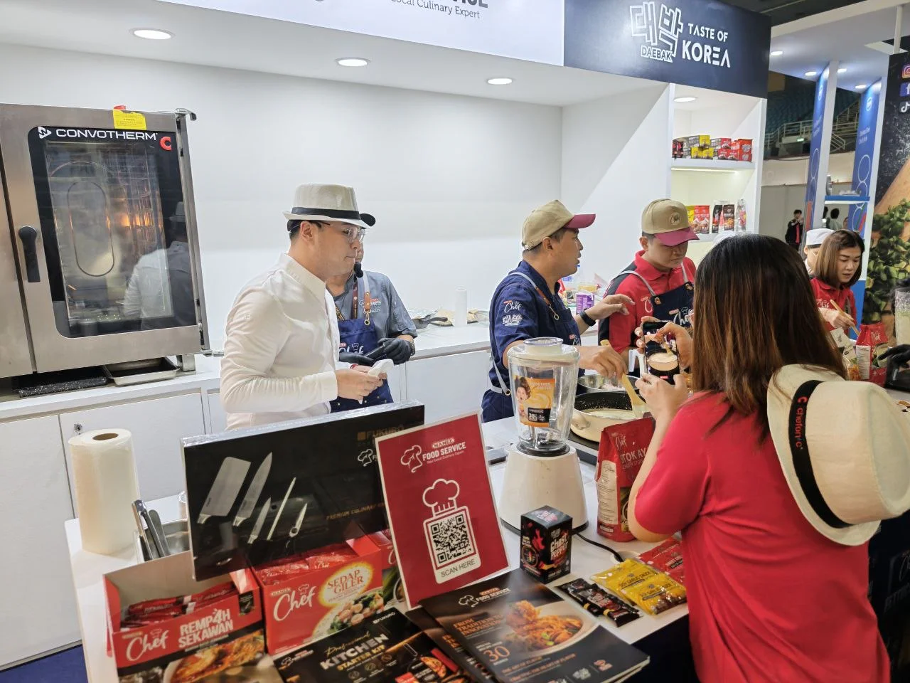 A chef serves tasting samples at a food service counter on the trade floor.